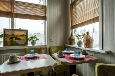 a dining room with two tables and chairs and windows at Hof van Schoorl in Schoorldam