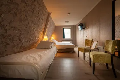 a hotel room with two beds and a table and chairs at Hof van Schoorl in Schoorldam