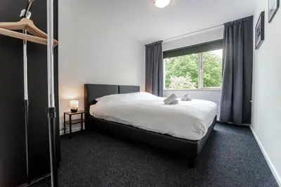 a bedroom with a bed and a large window at Zandvoort North Spacious 2 bedroom apartment in Zandvoort