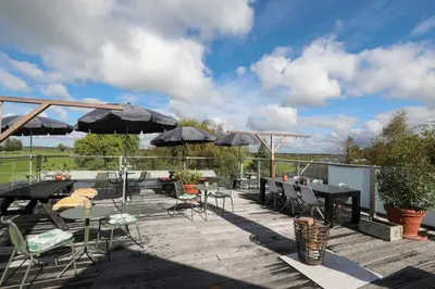 a deck with tables and chairs and umbrellas at Valerius Boutique Hotel in Wormer