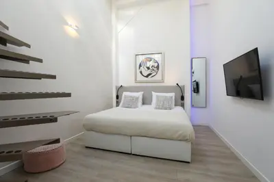 a white bedroom with a bed and a flat screen tv at Valerius Boutique Hotel in Wormer