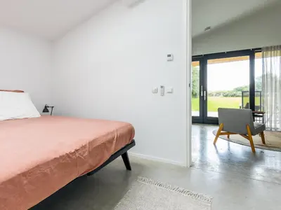 a bedroom with a bed and a chair and a window at De Duinlopers- appt Zilt Zand- Strand, duinen en nabij cultuur steden in Castricum