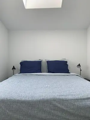 a bed with two blue pillows on top of it at De Duinlopers- appt Zilt Zand- Strand, duinen en nabij cultuur steden in Castricum