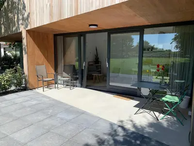 a patio with chairs and tables in front of a building at De Duinlopers- appt Zilt Zand- Strand, duinen en nabij cultuur steden in Castricum
