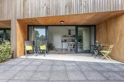a patio with chairs and a table in front of a building at De Duinlopers- appt Zilt Zand- Strand, duinen en nabij cultuur steden in Castricum