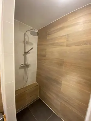 a bathroom with a shower with a wooden wall at The wave in Zandvoort