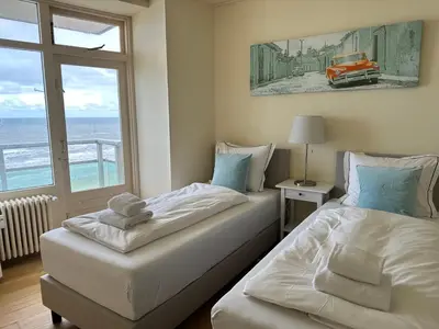 two beds in a room with a view of the ocean at The wave in Zandvoort
