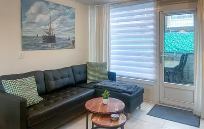 a living room with a leather couch and a table at Pet Friendly Home In Egmond Aan Zee in Egmond aan Zee
