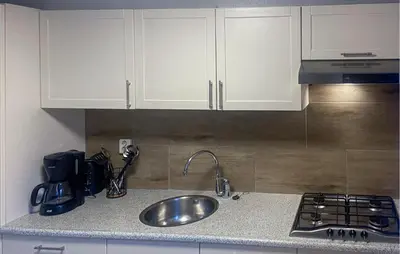 a kitchen with white cabinets and a sink and a stove at Pet Friendly Home In Egmond Aan Zee in Egmond aan Zee