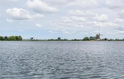 a large body of water with a windmill in the distance at Huis Nr 5 in Woubrugge