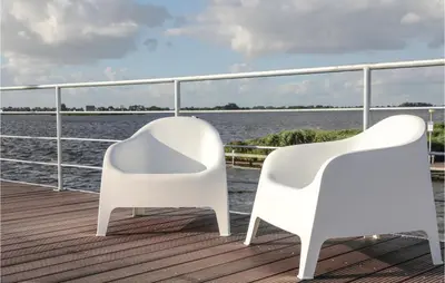 two white chairs sitting on a pier near the water at Aqualiving in Aalsmeer