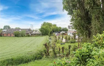 a field of grass with houses in the background at Huis Nr 4 in Woubrugge