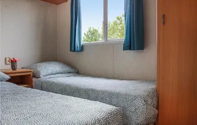 a bedroom with two beds and a window with blue curtains at Huis Nr 3 in Woubrugge