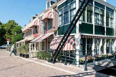 a woman walking past a building on a street at Hof van Holland Hotel in Edam