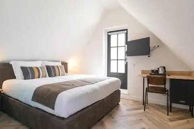 a bedroom with a bed and a desk with a computer at Hof van Holland Hotel in Edam