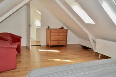 a room with a bed and a dresser and a staircase at Fiddler's Hoorn in Zwaag