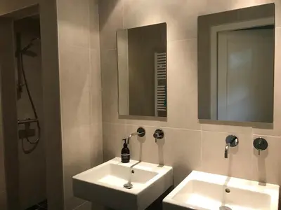 a bathroom with two white sinks and a mirror at Fiddler's Hoorn in Zwaag