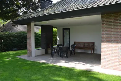 a patio with chairs and a table in a yard at Fiddler's Hoorn in Zwaag