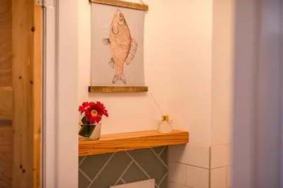 a shelf with a fish picture and a vase of flowers at Beachhouse Anna, 1 minute walk to the beach and centre of Katwijk, Free private parking next to the house ! in Katwijk aan Zee