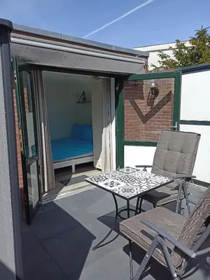 a patio with a table and chairs and a bed at Little Beach Place in Zandvoort
