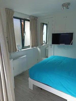 a bedroom with a bed and a flat screen tv at Little Beach Place in Zandvoort