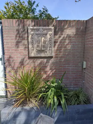 a stone plaque on a brick wall with plants at Little Beach Place in Zandvoort