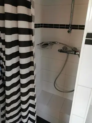 a bathroom with a shower with a black and white shower curtain at loft boat in Amsterdam