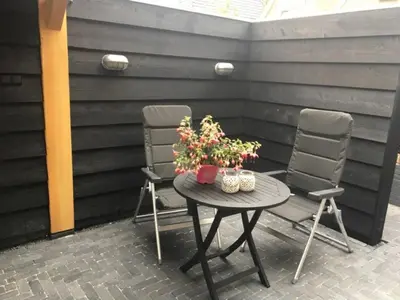 two chairs and a table with flowers on a patio at Appartement RoMi in Koedijk