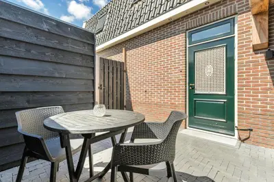 a table and chairs on a patio with a green door at Appartement RoMi in Koedijk