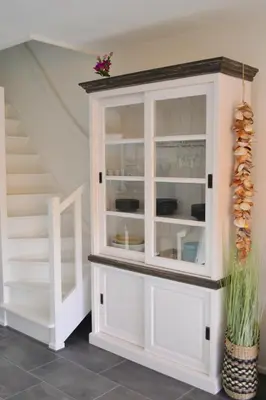 a white cabinet with glass doors next to a staircase at Beachy Chic Zandvoort in Zandvoort
