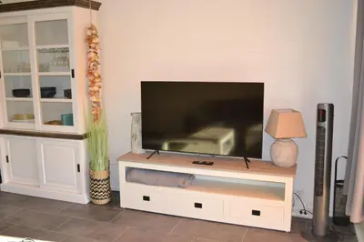 a flat screen tv sitting on top of a white entertainment center at Beachy Chic Zandvoort in Zandvoort