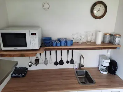 a kitchen with a counter with a microwave and a sink at Have a nice stay! - Holiday Home de Witte Raaf with garden and hottub in Noordwijk aan Zee