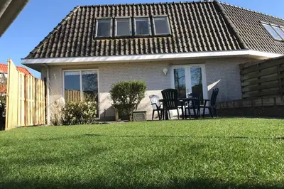 a house with a table and chairs in the yard at Have a nice stay! - Holiday Home de Witte Raaf with garden and hottub in Noordwijk aan Zee