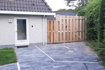 a garage with a wooden gate and a driveway at Have a nice stay! - Holiday Home de Witte Raaf with garden and hottub in Noordwijk aan Zee