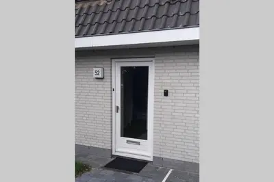a white door on a white brick building at Have a nice stay! - Holiday Home de Witte Raaf with garden and hottub in Noordwijk aan Zee