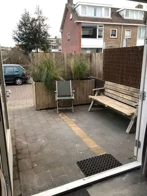 a view of a patio with a bench and a fence at Have a nice stay! - Beach Cottage free parking in Noordwijk aan Zee