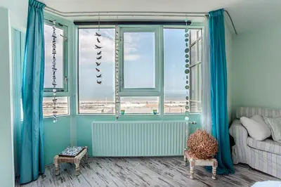 a room with blue curtains and a couch and a window at Beach Suite Sand in Zandvoort