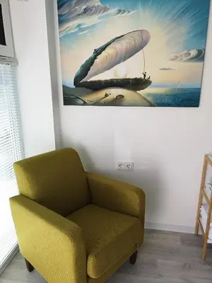 a yellow chair in a room with a painting on the wall at Beach Studio, No Sea View, Public Paid Parking in Zandvoort