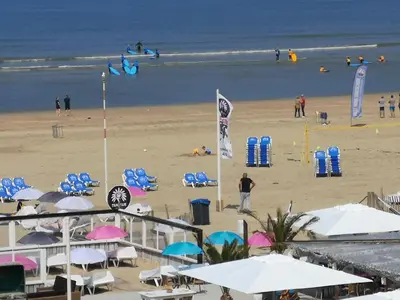 a beach with chairs and umbrellas and people on the beach at Beach Studio, No Sea View, Public Paid Parking in Zandvoort