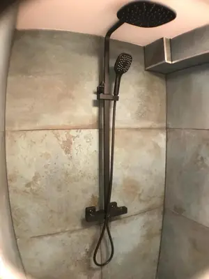 a shower with a black shower head in a bathroom at Beach Studio, No Sea View, Public Paid Parking in Zandvoort