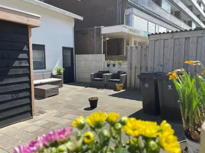 a courtyard with flowers and furniture in a building at Beach House Parallel in Noordwijk
