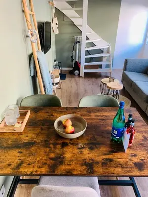a wooden table with a bowl of fruit and a bottle at Beach House Parallel in Noordwijk
