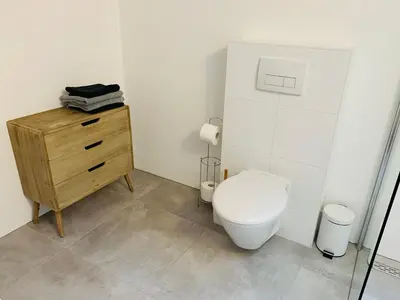 a bathroom with a toilet and a wooden dresser at Beach House Parallel in Noordwijk
