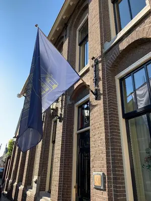 a flag is hanging on the side of a building at Oude Postkantoor de Rijp in De Rijp