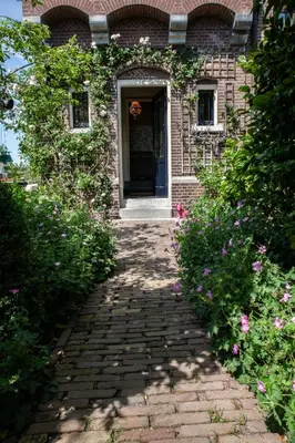 a brick house with a walkway leading to a door at Oude Postkantoor de Rijp in De Rijp