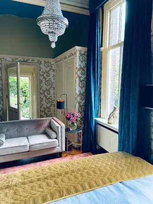 a bedroom with a couch and a window and a chandelier at Oude Postkantoor de Rijp in De Rijp