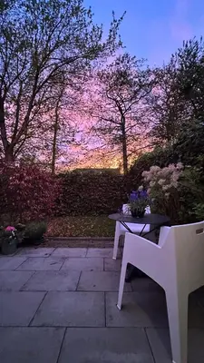 a patio with a table and a bench and flowers at Luxe B&B 