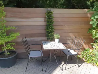 a table and chairs in front of a wooden fence at Casa Allegria - Zuiderbosch in Bergen