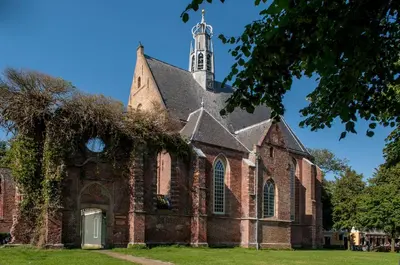an old church with a tower on a grass field at Casa Allegria - Zuiderbosch in Bergen