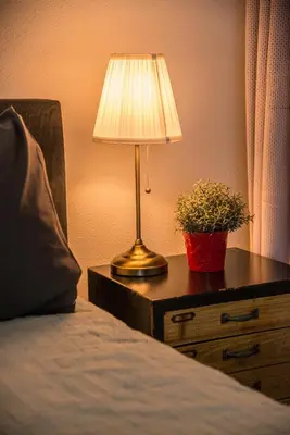 a lamp on a table next to a bed with a plant at Casa Allegria - Zuiderbosch in Bergen